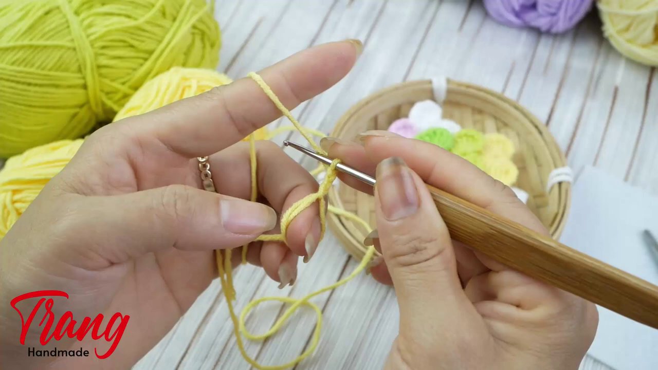 Các bước tạo vòng ma thuật với len màu hồng trên nền gỗ tự nhiên.