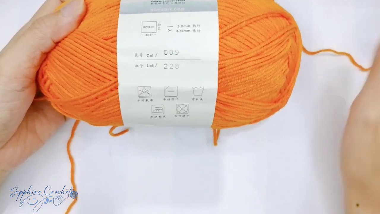 Hai chiếc kim móc len với kích cỡ khác nhau được đặt cạnh cuộn len.