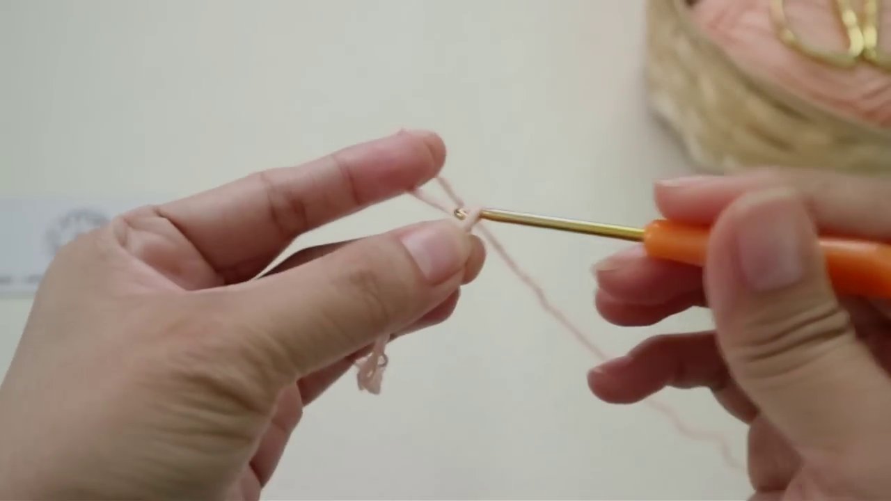 Bàn tay đang luồn kim vào một chân len cụ thể để tạo vòm cho cánh hoa.