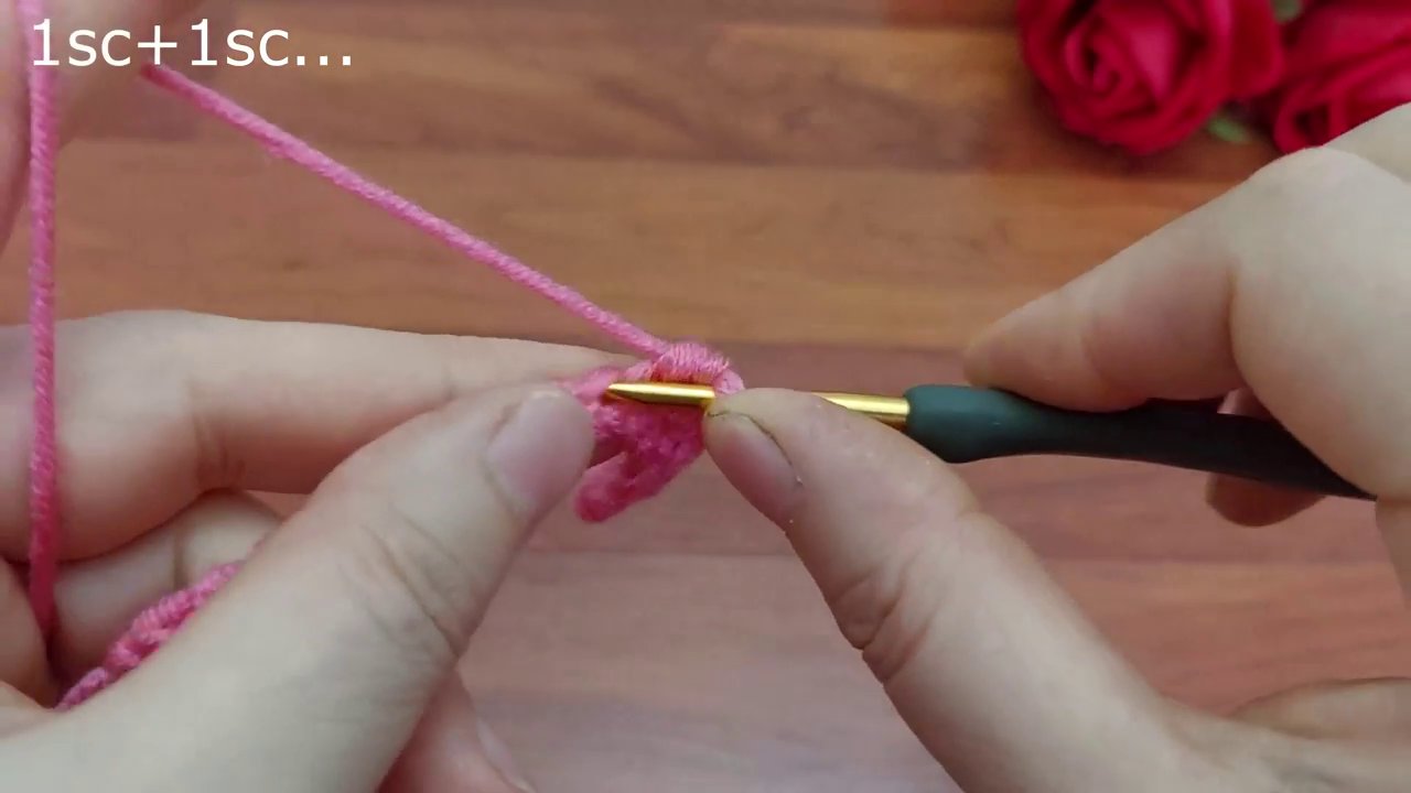 Miếng crochet nhỏ màu hồng được giữ trong lòng bàn tay, hình thành phần đáy túi.