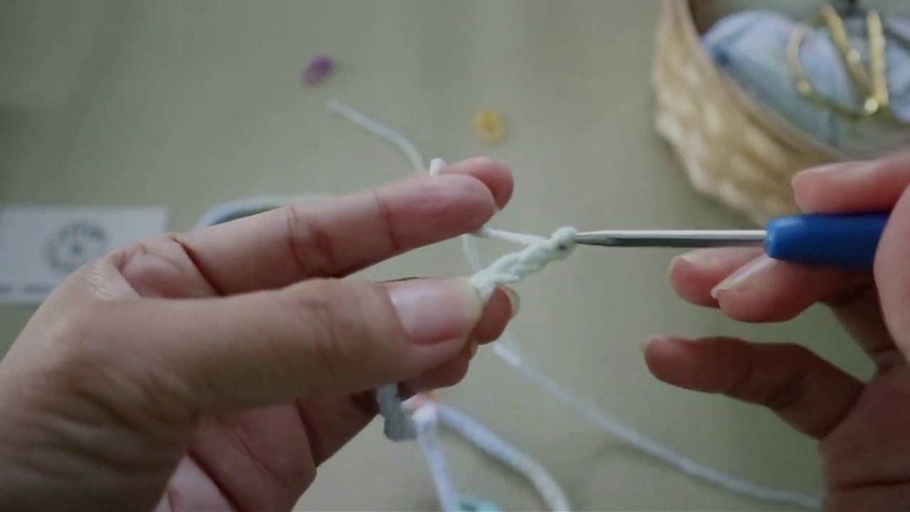 Chi tiết cách luồn kim qua các vòng len để tạo thành hình lỗ.