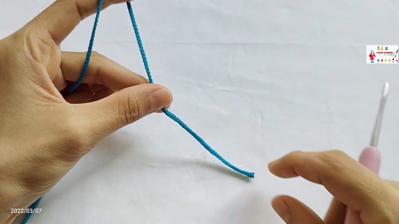 Cách tạo nút thắt slip knot, với đuôi len nằm phía dưới và một vòng len đã nằm trên kim.