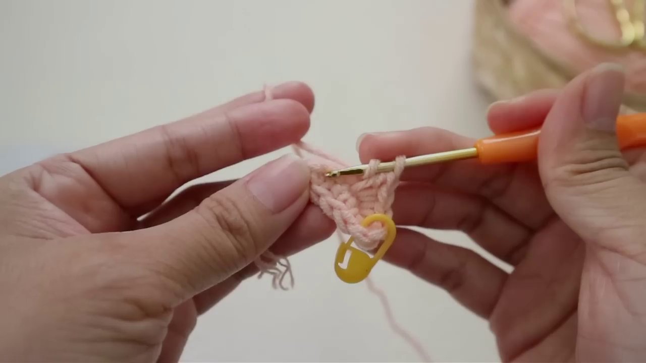 Người viết giơ chiếc kẹp thành phẩm trên nền cỏ xanh.
