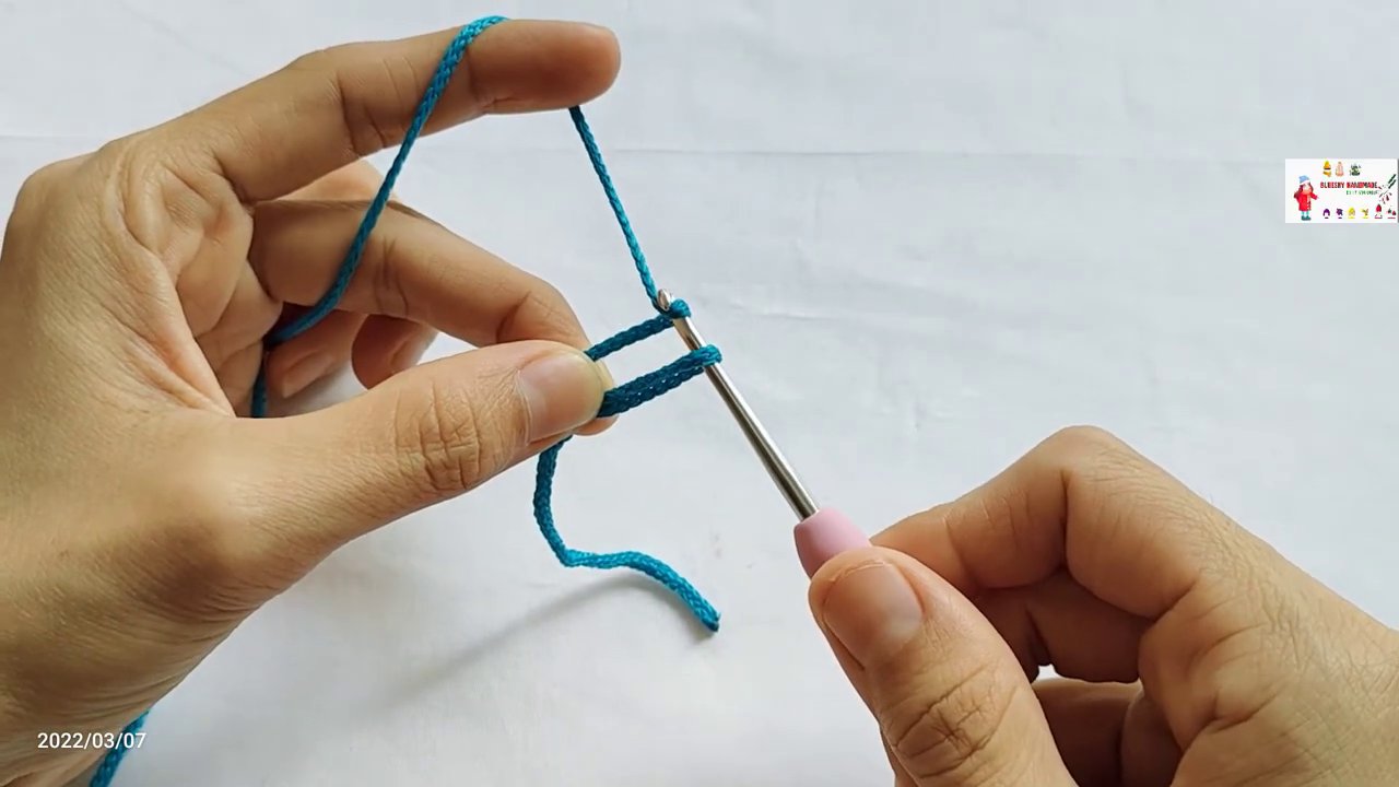 Động tác quấn sợi (yarn over) qua thân kim móc, bước chuẩn bị để thực hiện mũi bính.