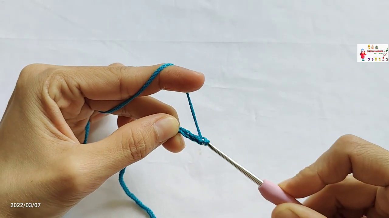 Hình ảnh một dây mũi bính dài đang được thực hiện, kim móc đang kéo sợi qua vòng len.