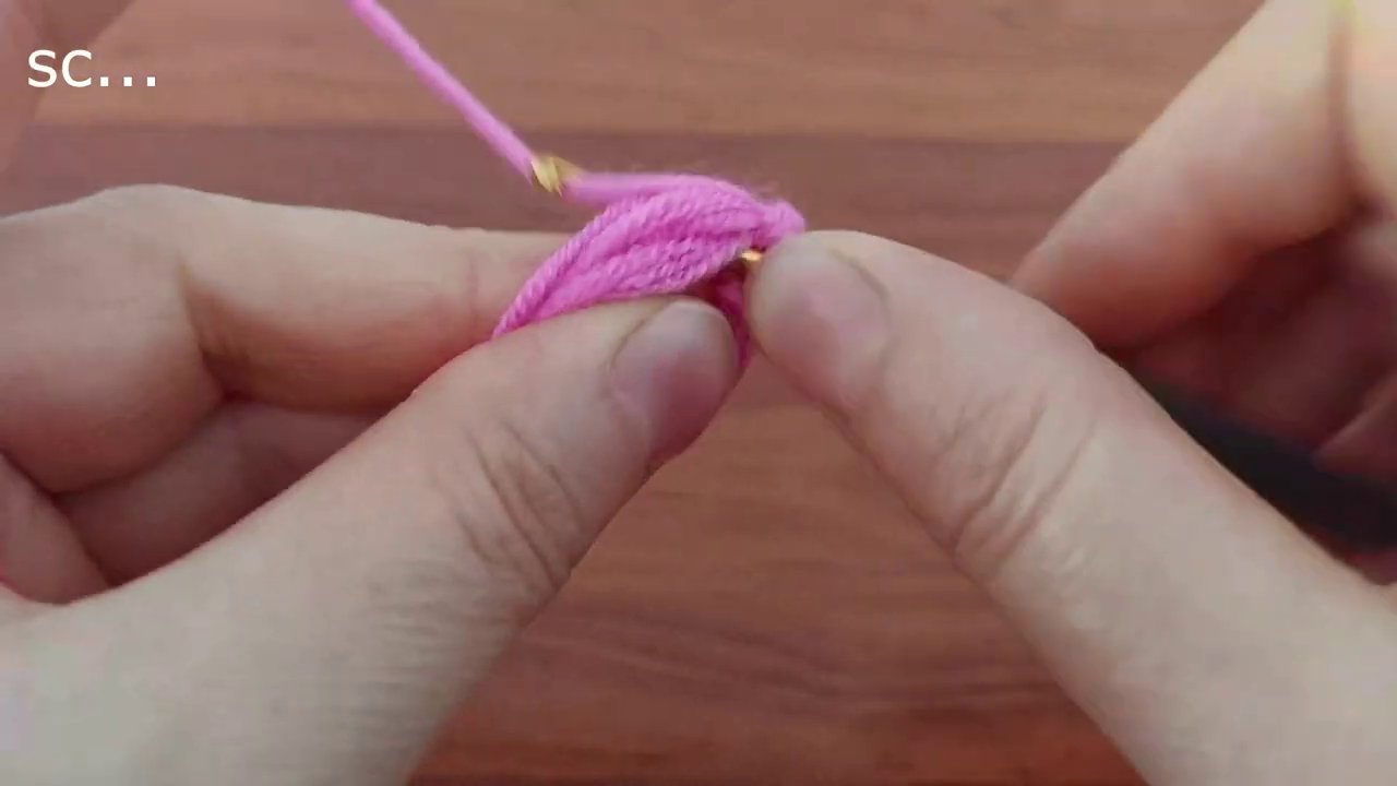 Bông hoa crochet màu hồng được giữ trong lòng bàn tay sau khi định hình xong.