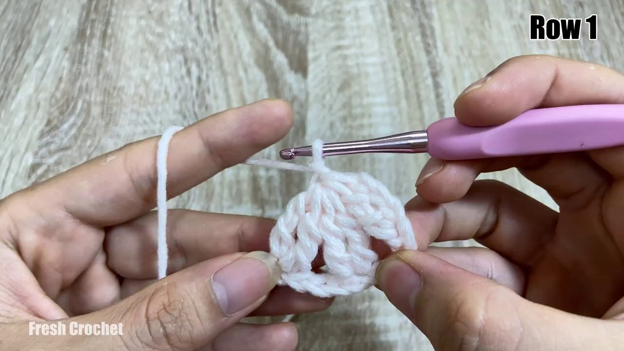 Một chú thỏ bông nhỏ màu trắng đang được móc dở, phần thân đã hoàn thiện, chỉ còn ta i và ta y.
