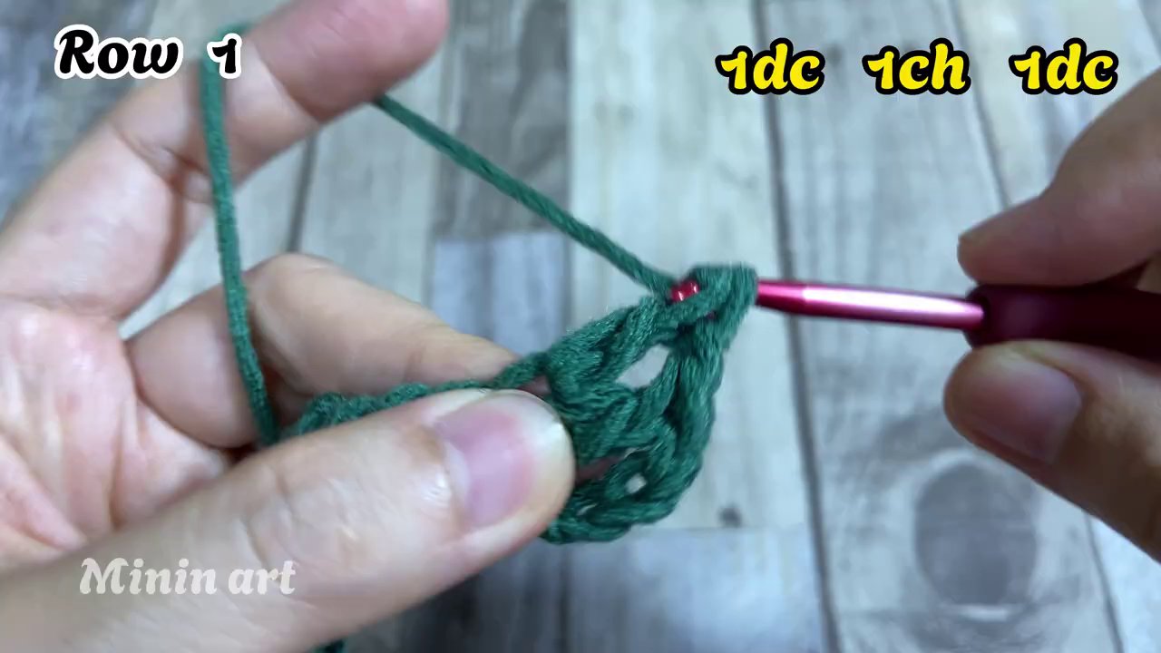 Tay phải đang chèn kim và o thân mũi dc của hàng dưới để thực hiện mũi Fptr, ta y trái giữ chặt phần len đã móc.