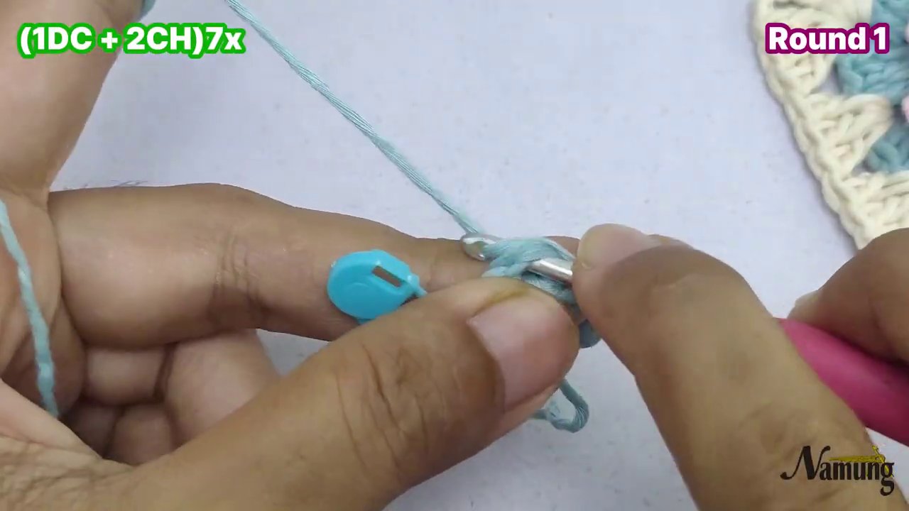 Đôi ta y đang móc sợi len hồng và o các khoảng trống của vòng 1, với dòng chữ "3CH + Slip Stitch" và "Round 2" trên màn hình.