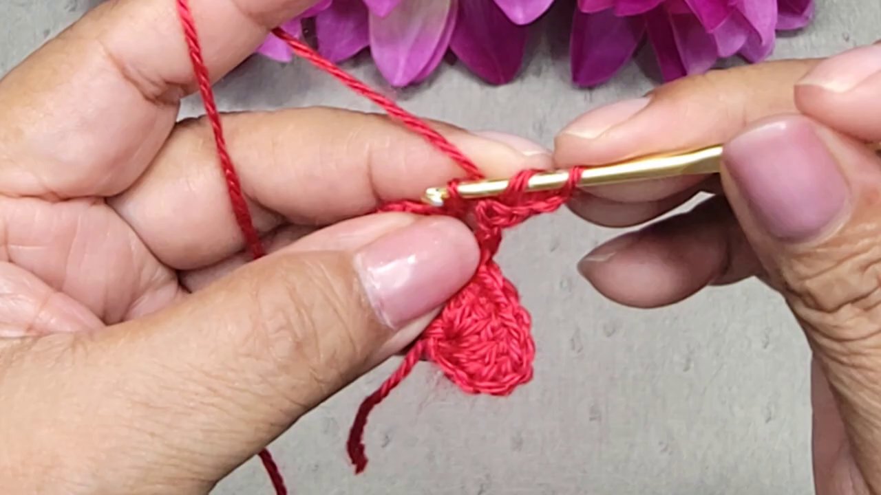Một sản phẩm móc len đang được thực hiện, với các marker len nhiều màu được gắn các h đều nhau.