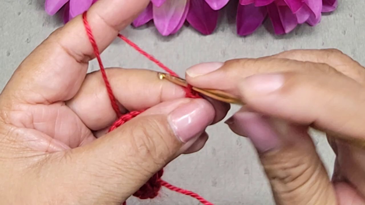 Một bàn ta y đang nhẹ nhàng tháo một đoạn len đã móc để sửa lỗi.