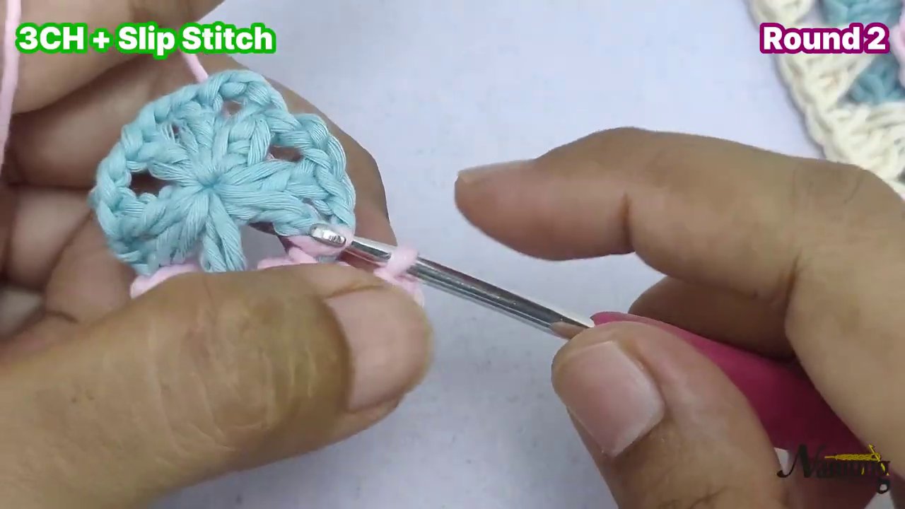 Cận cảnh một granny s quare hoàn chỉnh với hai màu xanh nhạt và hồng, các mũi móc đều và đẹp.