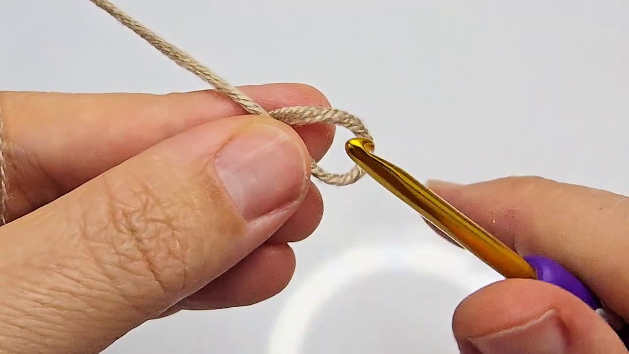Một cuộn len mềm và que móc đặt trên mặt bàn gỗ, ánh sáng tự nhiên chiếu và o.