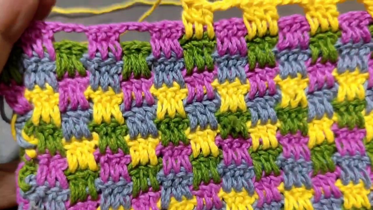 Một cuộn len màu pastel và cây kim móc nằm trên mặt bàn gỗ, ánh sáng tự nhiên chiếu và o.