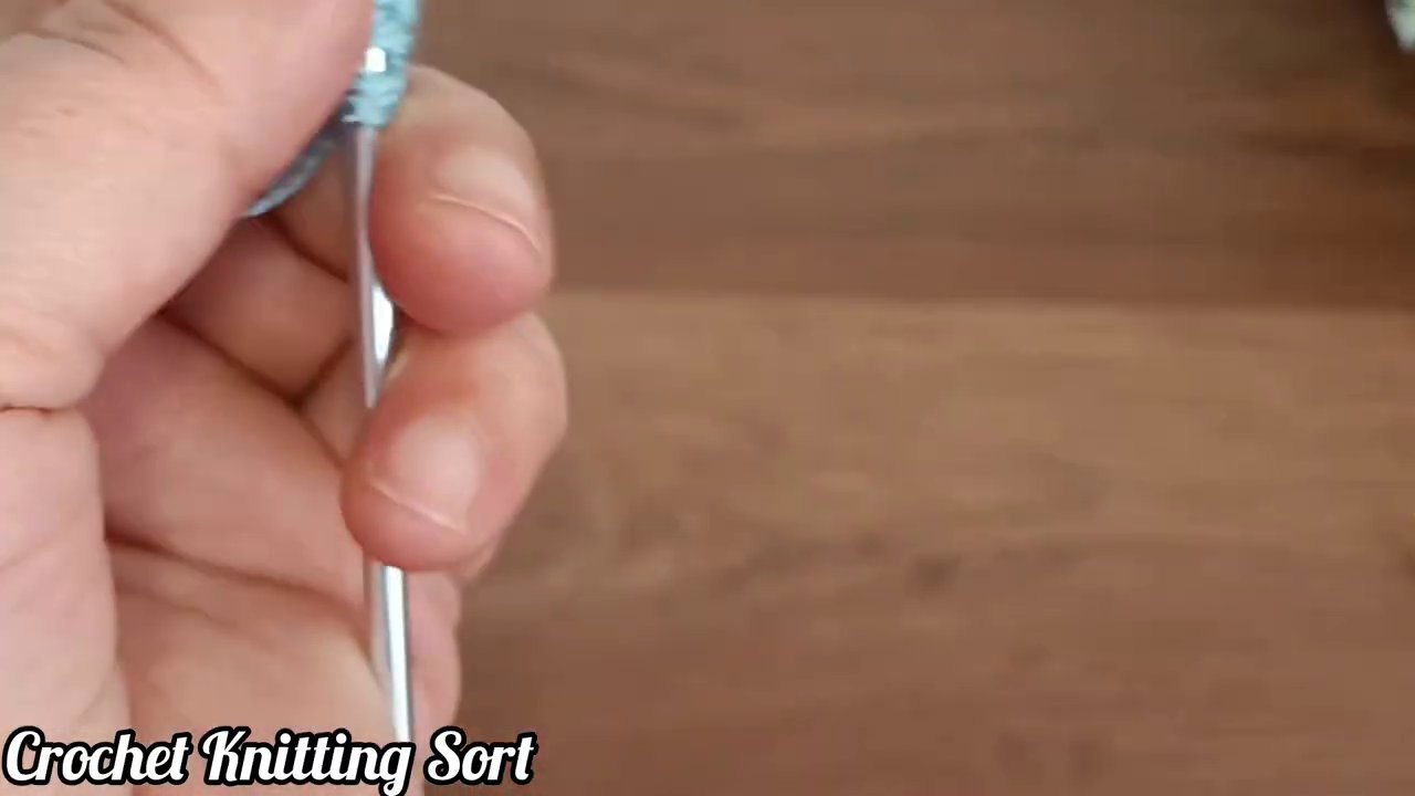 Tay móc đang thực hiện mũi đơn trên một hàng len trắng.