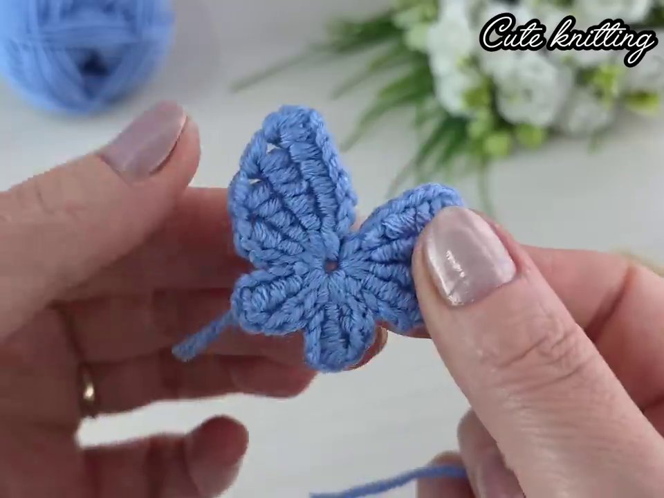 Bàn ta y đang cầm kim móc và cuộn len, chuẩn bị cho một dự án mới.